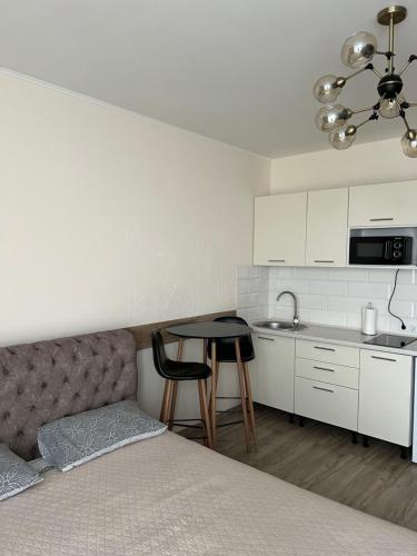 a bedroom with a bed and a table and a kitchen at Апартаменти-студія на Герцена in Chernivtsi