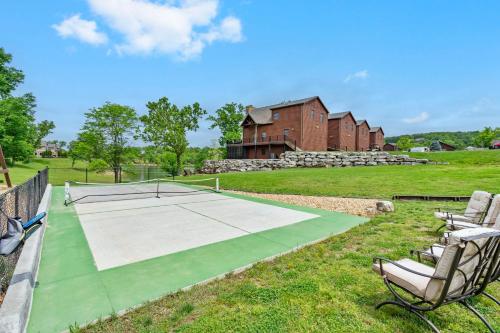 a tennis court with two chairs and a house at Luxury Lakefront Chalet Resort 2 Pools FREE Amenities Dock Kayaks Waterslide in Lampe