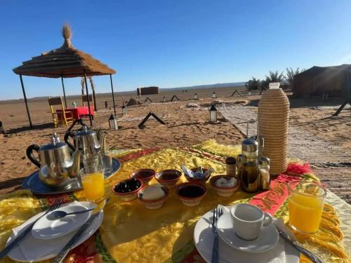 a table with food and drinks on the beach at Camp Desert Sky in Merzouga
