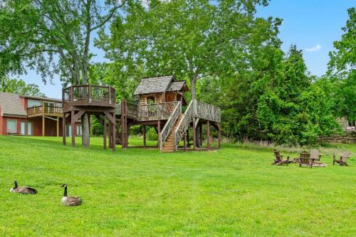 a tree house in a field with geese in the grass at Luxury Lakefront Chalet Resort 2 Pools FREE Amenities Dock Kayaks Waterslide in Lampe