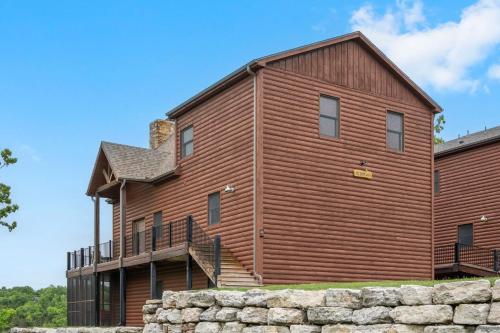 a large wooden building with a stone wall at Luxury Lakefront Chalet Resort 2 Pools FREE Amenities Dock Kayaks Waterslide in Lampe
