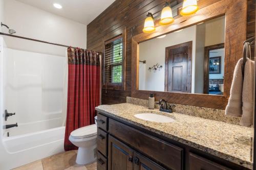 une salle de bain avec un lavabo, des toilettes et un miroir dans l'établissement Chalets Resort Luxury Lakefront Villa Family Friendly 2 Pools Free Amenities, à Lampe