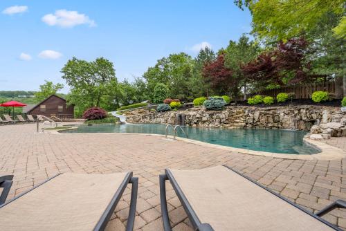 a swimming pool with two chairs and a stone wall at 8 Bed Luxury Lakefront Villa Amazing View 2 Pools Free Resort Amenities Dock in Lampe