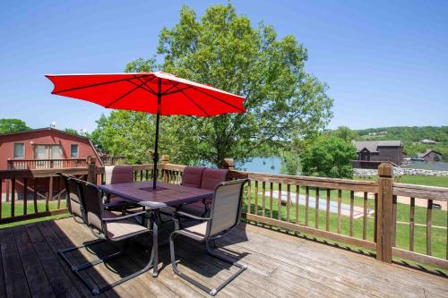 a patio table with a red umbrella on a deck at Chalets Resort LAKEFRONT Cottage Free Amenities Amazing views Kayaks 2 Pools in Lampe