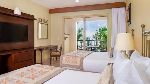 a bedroom with two beds and a television and a balcony at Villa del Arco Beach Resort & Spa in Cabo San Lucas