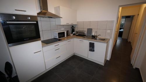 a small kitchen with white cabinets and a microwave at Consci apartments in Antwerp