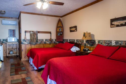 a bedroom with two beds with red sheets at Mountain Aire Cottages, Inn, & Glamping in Clayton