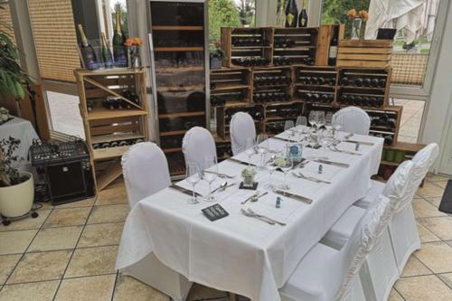 a table with white chairs in a wine cellar at Hotel Empfinger Hof, Sure Hotel Collection by Best Western in Empfingen