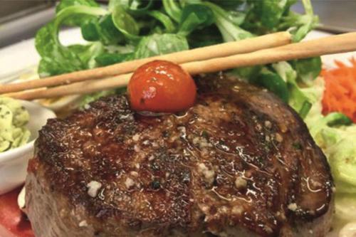 a piece of meat with chopsticks on a plate with salad at Hotel Empfinger Hof, Sure Hotel Collection by Best Western in Empfingen