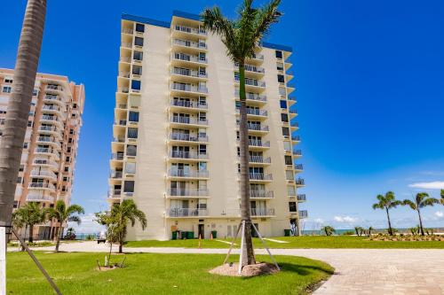 a tall building with palm trees in front of it at Estero Beach & Tennis 804- C by Sun Palace Vacations in Fort Myers Beach