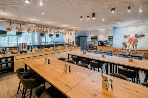 ein Restaurant mit Holztischen und Stühlen und einer Küche in der Unterkunft Best Western Hotel Arabellapark Muenchen in München