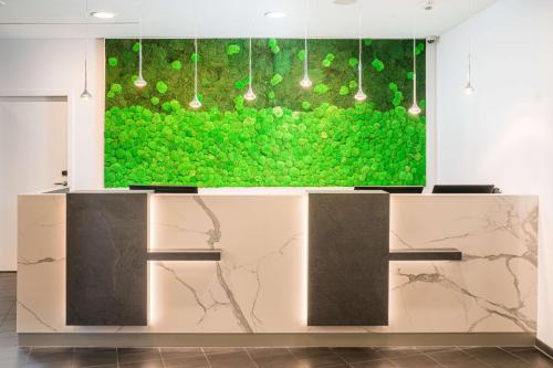 a lobby with a large green wall with lights at Best Western Hotel Airport Frankfurt in Frankfurt/Main