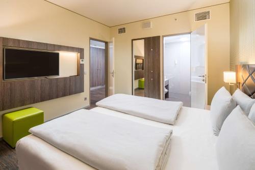 a hotel room with two beds and a flat screen tv at Best Western Hotel Airport Frankfurt in Frankfurt/Main