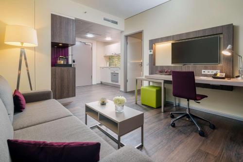 a living room with a couch and a desk at Best Western Hotel Airport Frankfurt in Frankfurt/Main