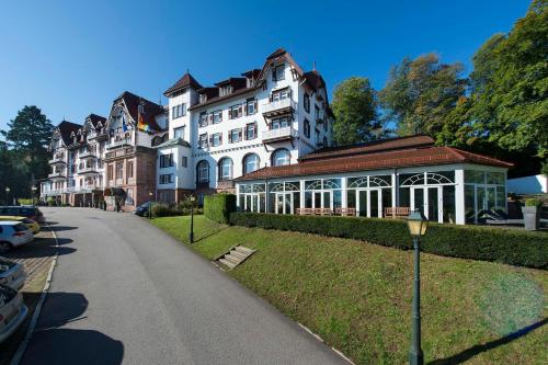 a large white building with a gazebo next to a street at Das Palmenwald Schwarzwaldhof, BW Signature Collection in Freudenstadt