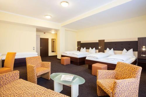 a hotel room with two beds and chairs at Best Western Hotel Augusta in Augsburg