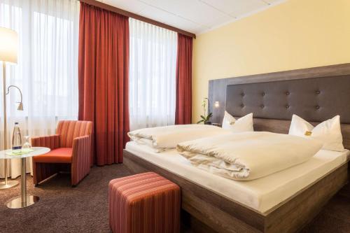 a hotel room with a bed and a chair and a table at Best Western Hotel Augusta in Augsburg