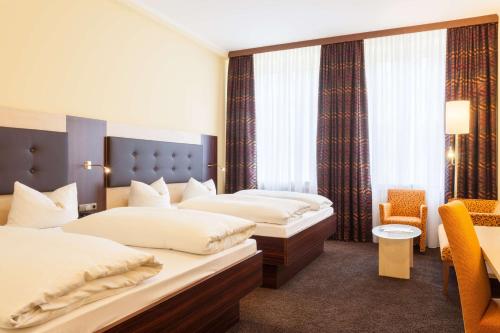 a hotel room with two beds and a chair at Best Western Hotel Augusta in Augsburg