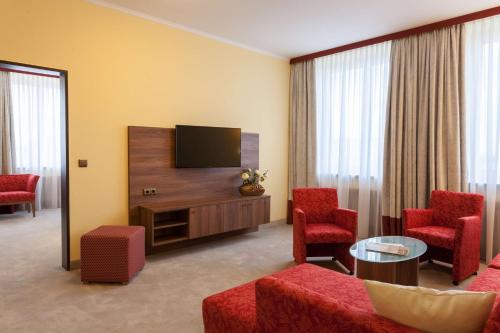 a living room with a television and red chairs at Best Western Hotel Augusta in Augsburg