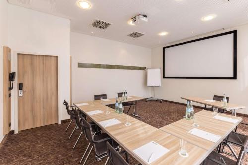 a conference room with tables and chairs and a projection screen at Best Western Plus Hotel Koeln City in Cologne