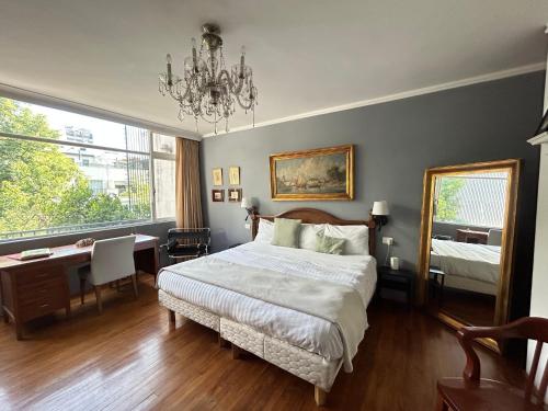 a bedroom with a bed and a desk and a chandelier at Lindas Suites Eugenio Sue in Mexico City