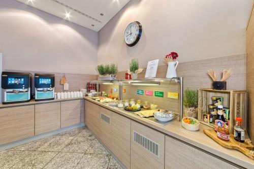 a kitchen with a counter with a clock on the wall at Best Western Plus Hotel Dresden City in Dresden