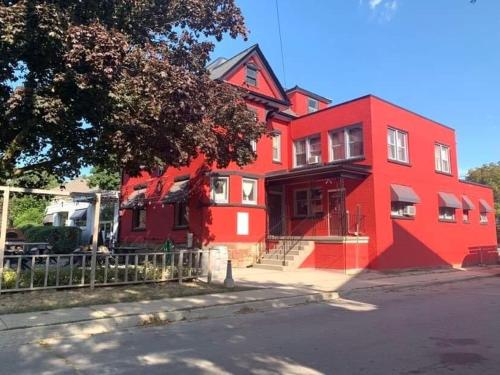 a red house with a fence in front of it at Lovely 1- bedroom Unit in Grimsby in Grimsby
