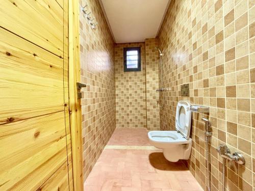 a bathroom with a toilet and a wooden door at Complexe Kariat Ayoub in Aït Zat