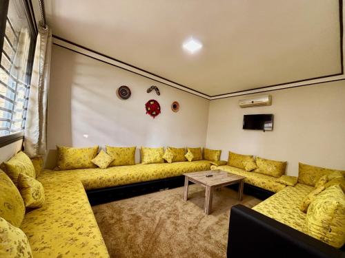 a living room with a yellow couch and a table at Complexe Kariat Ayoub in Aït Zat