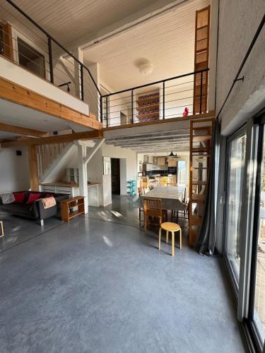 une grande chambre avec une table à manger et une mezzanine dans l'établissement Séjour cosy à Saint Nazaire, à Les Eymes