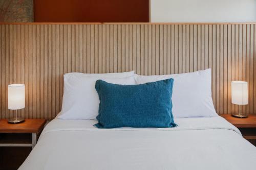 a bed with a blue pillow and two lamps at Aloe Village Aparthotel & Spa in La Paloma