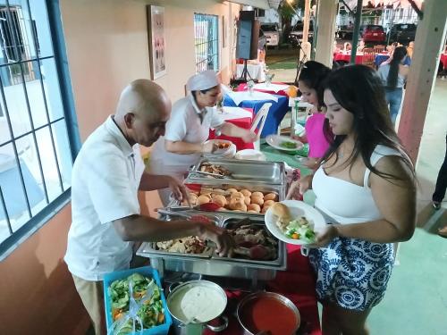 a group of people preparing food at a buffet at Hotel El Cocobolo Food&Rest Room 3 B&B WiFi AC Pkg Free Swimmingpool in Liberia