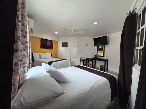 a hotel room with two beds and a television at Hotel Posada Mercy in Río Lagartos