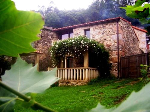 ein Steinhaus mit einem Holzzaun und einem Hof in der Unterkunft Casas Lucas - Carleo in Outes