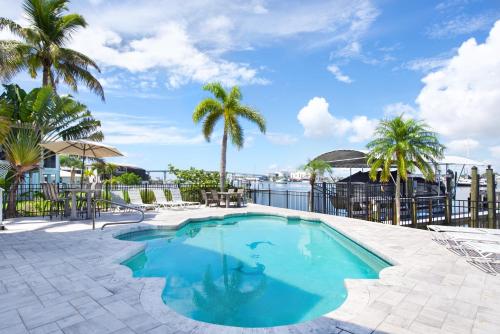 a swimming pool with palm trees and a body of water at Dock Holiday by Sun Palace Vacations in Fort Myers Beach