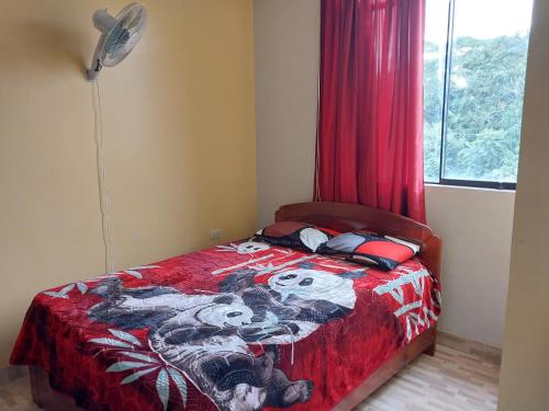 a bedroom with a bed with a red blanket and a window at Depart 3 camas in Moyobamba