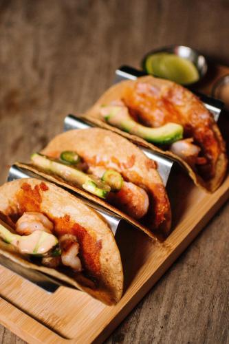 three sandwiches on a wooden plate on a table at Boskenvid Hotel - Romantic Treehouses & Skypool in Valle de Guadalupe