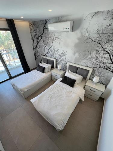 twee bedden in een kamer met bomen aan de muur bij Eva chalet in Deadsea in Al Kafrayn