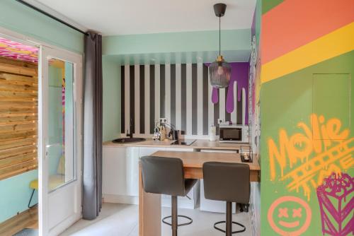 Il comprend une cuisine dotée d'un mur coloré avec une table et des chaises. dans l'établissement L'escapade - Jacuzzi & Sauna privés By SweetDreams, à Cagnes-sur-Mer