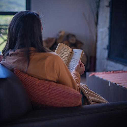 a woman sitting on a couch reading a book at AMANCIO Hotel & Cabañas in Villa Meliquina