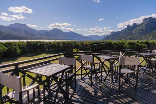 a deck with tables and chairs and a view of the mountains at AMANCIO Hotel & Cabañas in Villa Meliquina