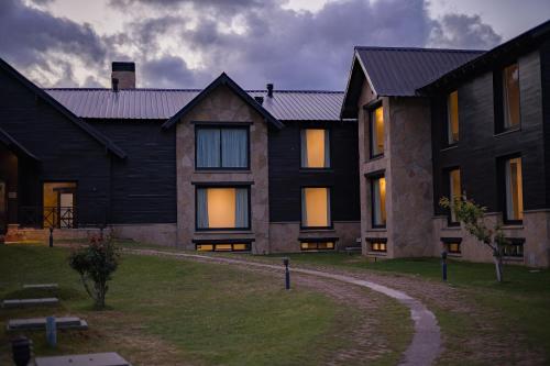 a large house with lights illuminating the windows of it at AMANCIO Hotel & Cabañas in Villa Meliquina
