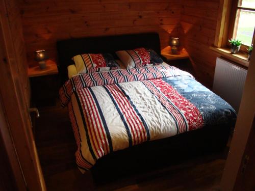 BoekelにあるChalet De Voetpompのベッドルーム1室(カラフルな掛け布団付きのベッド1台付)