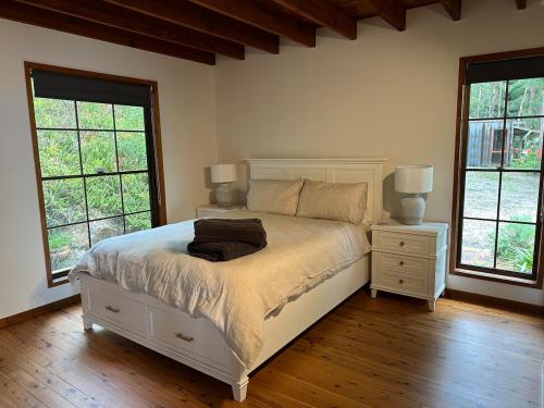 a bedroom with a bed with two night stands and two windows at Wren Abode 3 Bedroom A-Frame Home Lower Beechmont with Breakfast Basket in Lower Beechmont