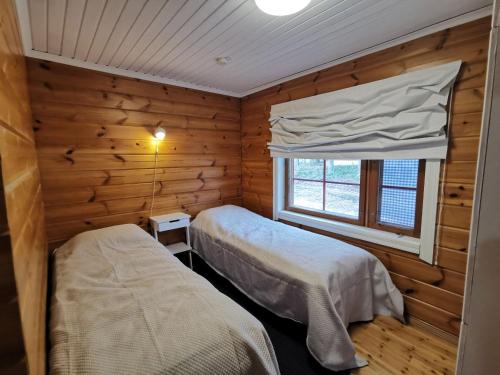 a bedroom with two beds in a log cabin at Villa Naukkari in Syöte