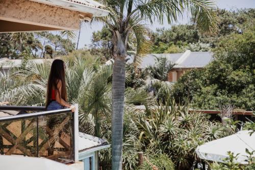 a woman sitting on a balcony looking at a palm tree at Aloe Village Aparthotel & Spa in La Paloma