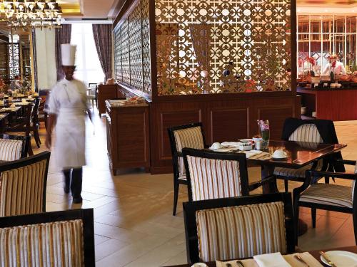 a chef walking through a restaurant with tables and chairs at Villa Rosa Kempinski in Nairobi