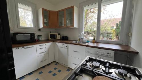 une cuisine avec des armoires blanches, un évier et un micro-ondes dans l'établissement Gîte Monatella, à Criel-sur-Mer