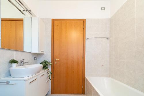 a bathroom with a sink and a wooden door at Martesana Terrace Flat with garage - Ospedale San Raffaele in Vimodrone