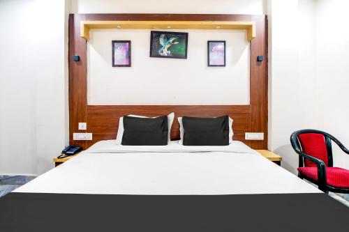 a bedroom with a white bed and a red chair at Super Hotel O Gurudwara Near RTC Complex in Visakhapatnam